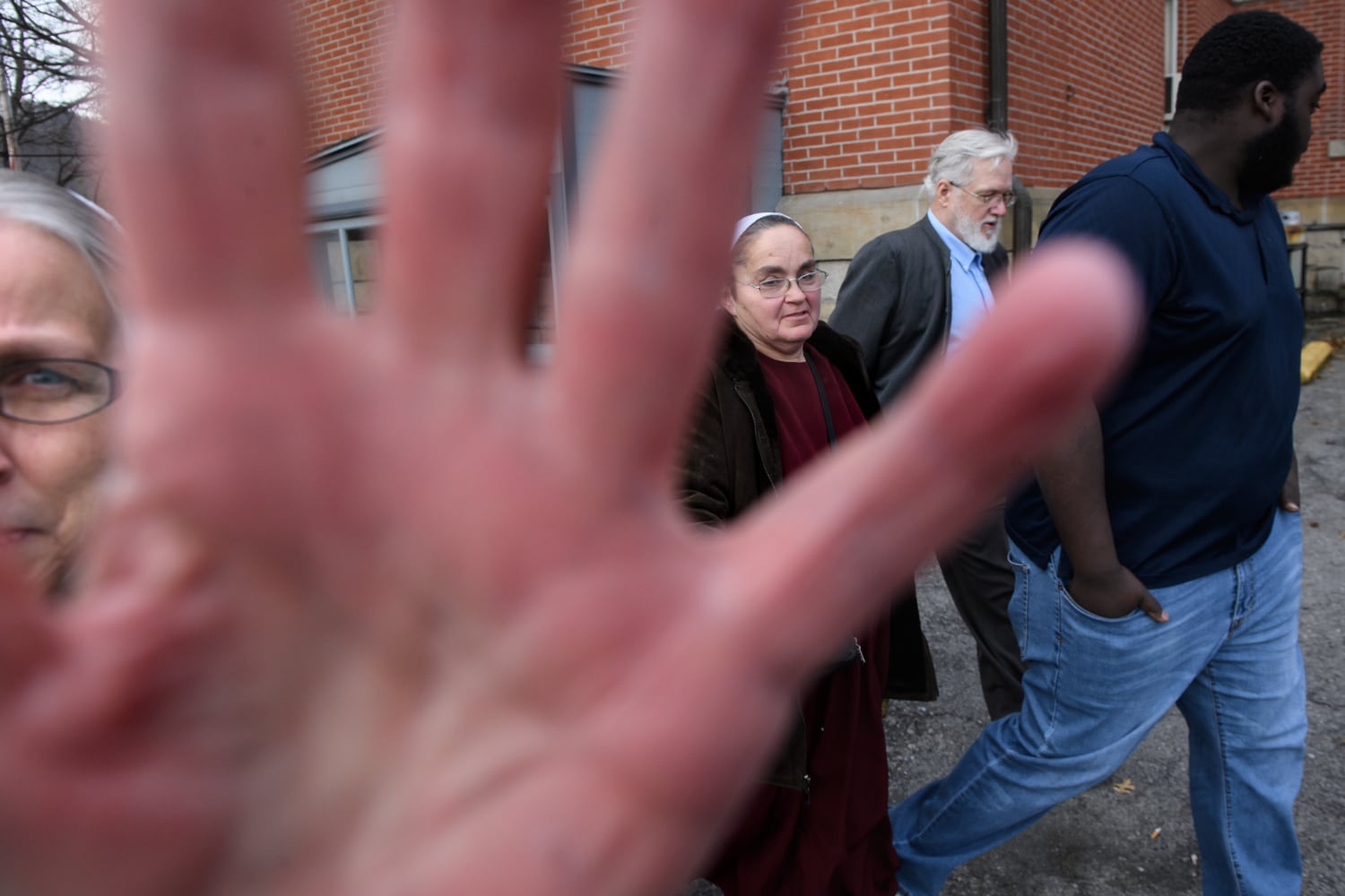 Maryann Fisher, left, of Alexandria, blocks the photographer’s camera as her husband, former pastor David Fisher, second from right, 64, leaves the Huntingdon County Courthouse after pleading no contest to a felony charge of endangering the welfare of a child in failure to report sexual abuse on Thursday, Jan. 10, 2019, in Huntingdon. Echoes of abuse coverups ring throughout Plain churches across the country in a culture that has historically emphasized a separation from the outside world. With them are the wife of Daniel R. Hostetler, Katie Hostetler, second from left, and Fisher’s adopted son, Charlie Fisher, far right.