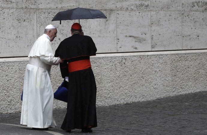 Cardinal Oscar Andres Rodriguez Maradiaga, right, makes space for Pope Francis under his umbrella as they leave at the end of a morning session of the Synod of Bishops at the Vatican, Thursday, Oct. 11, 2018. (Credit: AP Photo/Alessandra Tarantino.)