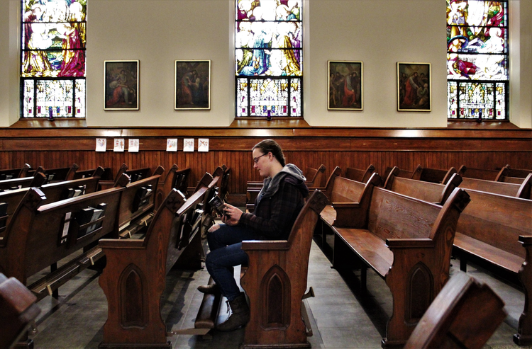 A woman reads a prayer book in the sanctuary of St. Mary Church in Appleton, Wis., on March 18,. Bishop David L. Ricken of Green Bay announced on March 17 that all public Masses in the diocese are suspended for the next four to eight weeks due to the coronavirus pandemic. (CNS photo/Brad Birkholz)