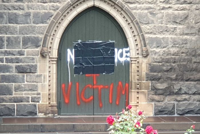 PHOTO: The cathedral doors and gates were spray-painted with obscenities and offensive images. (ABC News: Chris Le Page)