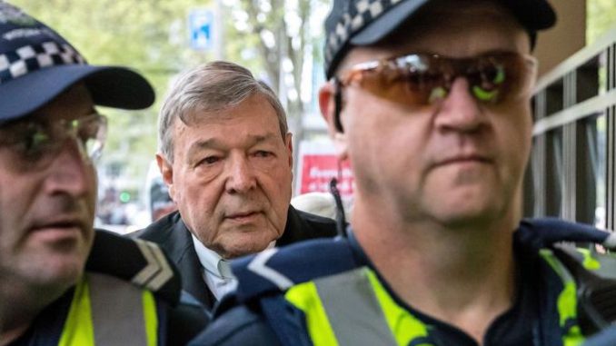 Australian Cardinal George Pell is seen in a 2017 file photo being escorted by police to the Melbourne Magistrates Court. (CNS photo/Mark Dadswell, Reuters)