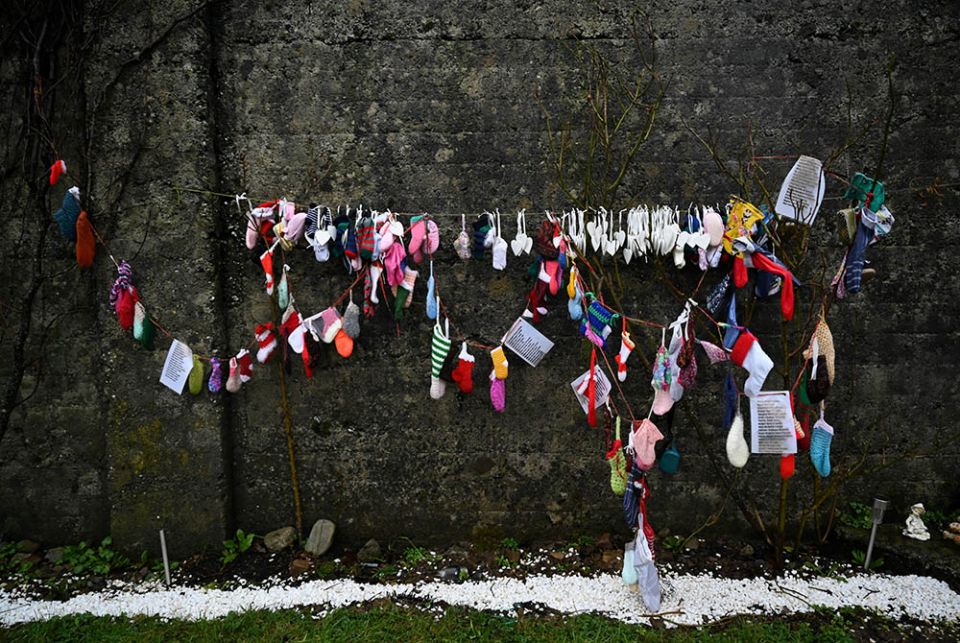 Baby clothing and other items hang from a wall at a cemetery in Tuam, Ireland, where the bodies of nearly 800 infants were uncovered at the site of a former Catholic home for unmarried mothers and their children. The photo was taken Jan. 12, the day a commission investigating the treatment of women in such homes released its report. (CNS/Clodagh Kilcoyne, Reuters)