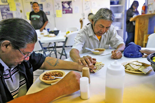 Nelson Simpson, left, and Chris Begay pray Wednesday before dinner at Catholic Charities in Farmington. (Jon Austria — The Daily Times)