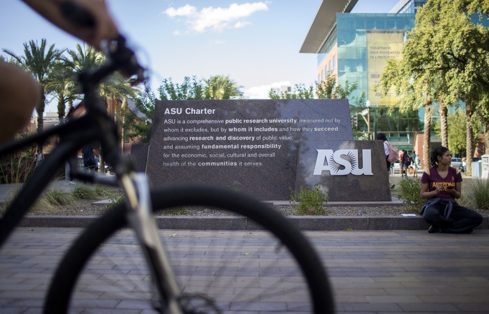 Students ride past a sign with the ASU charter on the Tempe campus on Thursday, Sept. 14, 2017.