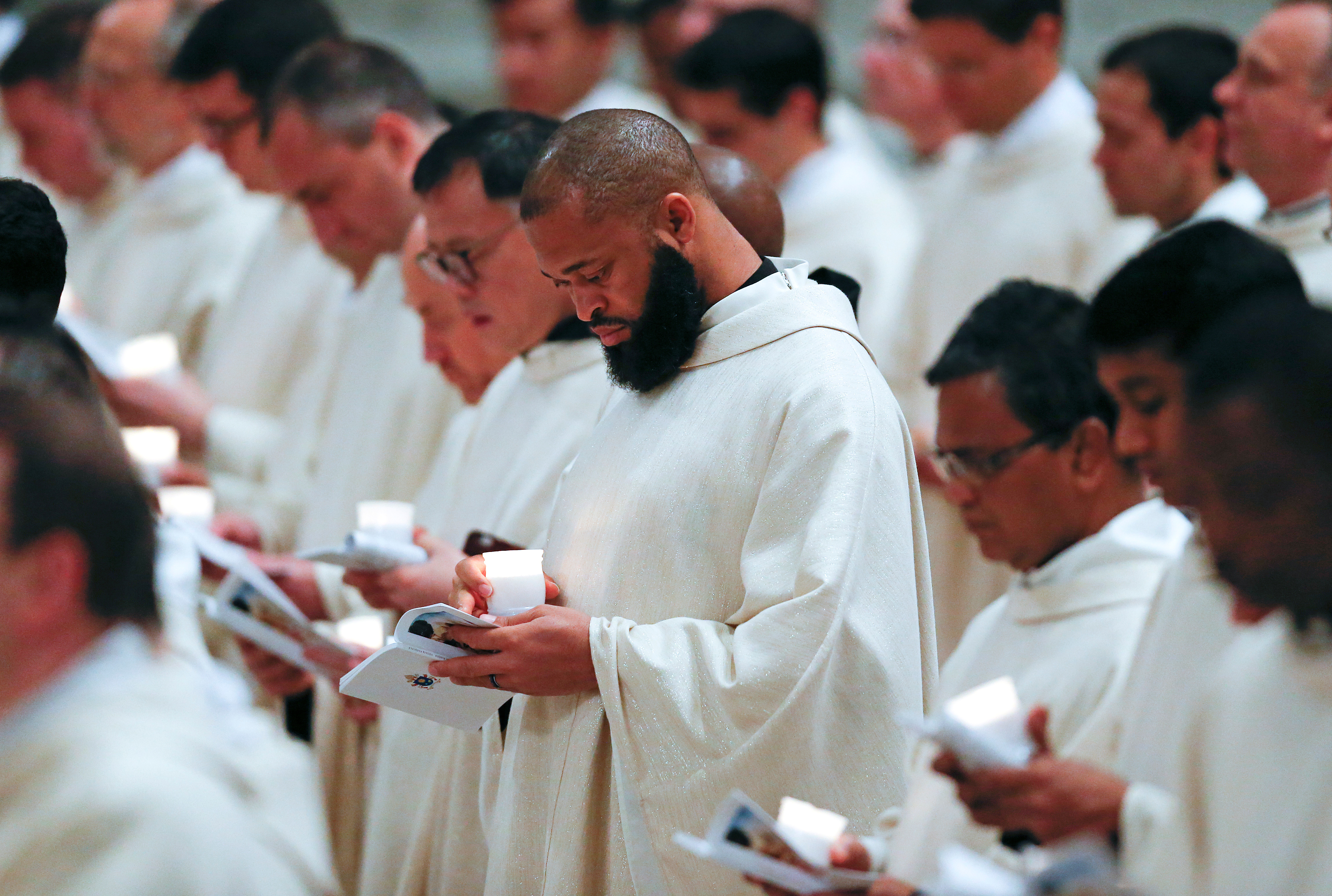 Priests hold candles during the Easter vigil mass led by Pope Francis in Saint Peter’s Basilica at the Vatican, March 31, 2018. REUTERS/Stefano Rellandini