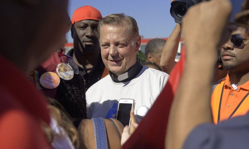 FILE - In this Saturday, July 7, 2018 file photo, The Rev. Michael Pfleger speaks to protesters before marching on the Dan Ryan Expressway in Chicago. A third man has come forward with allegations that Rev. Pfleger made an unwanted sexual advance against him as a teenager, following two brothers' allegations that the priest abused them decades ago when they were teens. (AP Photo/Annie Rice, File)