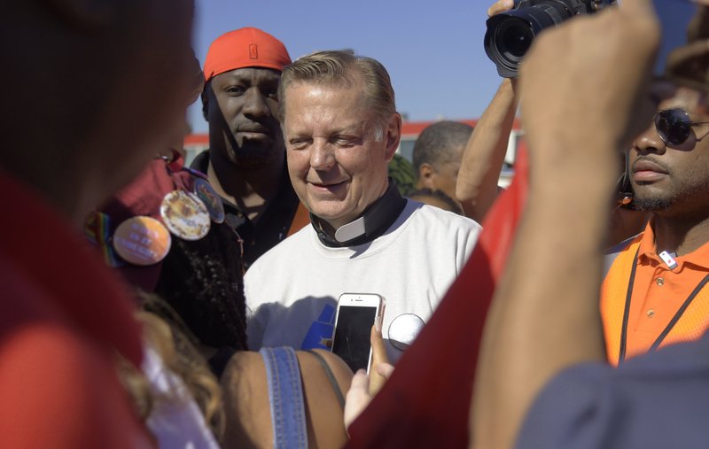 FILE - In this Saturday, July 7, 2018 file photo, The Rev. Michael Pfleger speaks to protesters before marching on the Dan Ryan Expressway in Chicago. A third man has come forward with allegations that Rev. Pfleger made an unwanted sexual advance against him as a teenager, following two brothers' allegations that the priest abused them decades ago when they were teens. (AP Photo/Annie Rice, File)