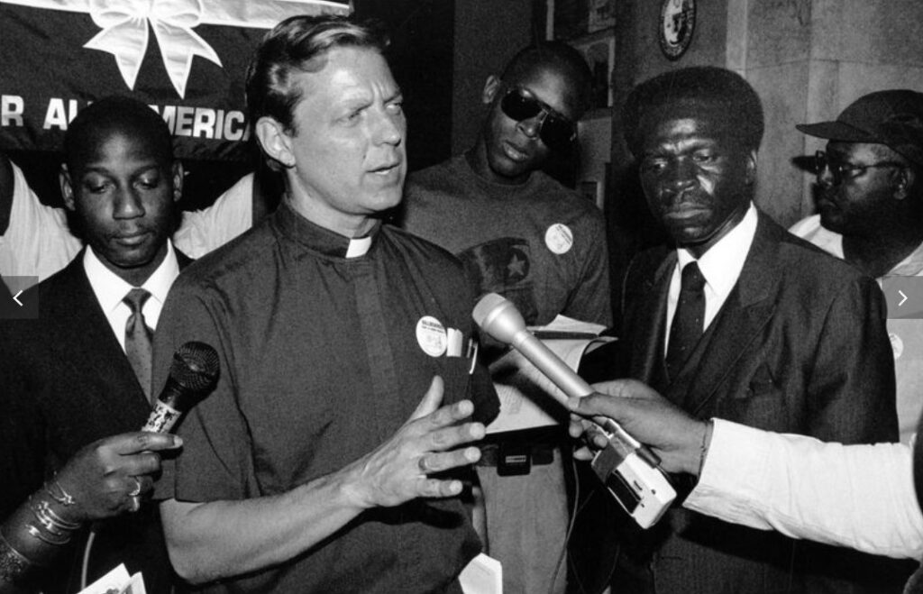 The Rev. Michael Pfleger talks with reporters at City Hall on July 23, 1991, protesting the saturation of billboards advertising alcohol and tobacco consumption to minority neighborhoods in Chicago. (Eduardo Contreras / Chicago Tribune)