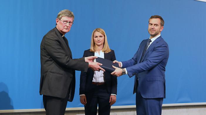 Prof. Gercke (r.) And Dr. Stirner hand over the report to Cardinal Woelki. [Prof. Gercke (r.) und Dr. Stirner übergeben das Gutachten an Kardinal Woelki]