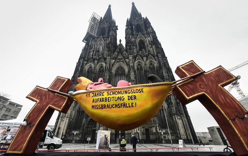 A carnival float depicting a sleeping Cardinal, reading '11 years of relentless processing of cases of abuse' is set in front of the Cologne Cathedral to protest against the Catholic Church in Cologne, Germany, Thursday, March 18, 2021. Faced with accusations of trying to cover up sexual violence in Germany's most powerful Roman Catholic diocese, the archbishop of Cologne Cardinal Rainer Maria Woelki publishes an independent investigation. (AP Photo / Martin Meissner)