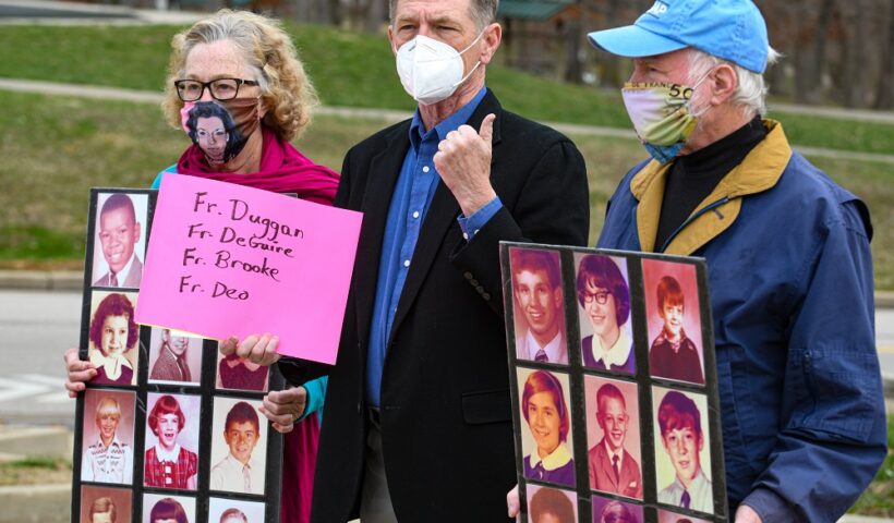 While David Chohessy, middle, addresses the media, Judy Jones, on left, and Steven Spaner hold up poster boards containing two dozen grade school photographs of known victims of abuse by Catholic priests. Jones is SNAP Midwest coordinator while Spaner is the coordinator for Australia Clohessy, the former national director of Survivors Network of those Abused by Priests, spoke Wednesday morning near the Catholic Chancery to ask Bishop Shawn McKnight to take more steps concerning the list of credibly accused clergy. Julie Smith/News Tribune