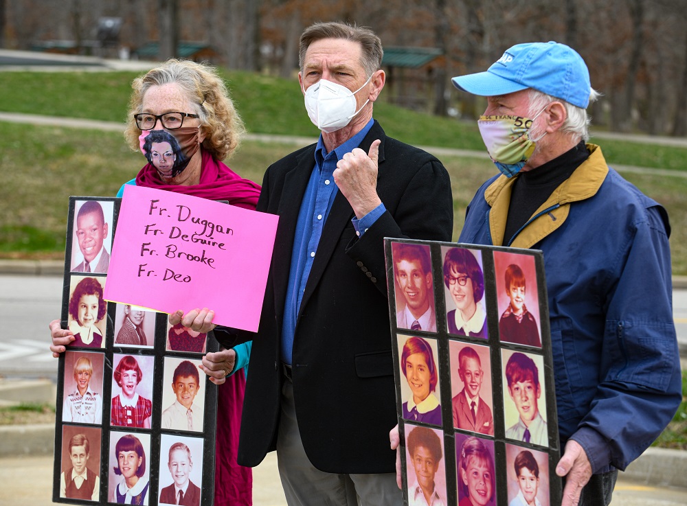 While David Chohessy, middle, addresses the media, Judy Jones, on left, and Steven Spaner hold up poster boards containing two dozen grade school photographs of known victims of abuse by Catholic priests. Jones is SNAP Midwest coordinator while Spaner is the coordinator for Australia Clohessy, the former national director of Survivors Network of those Abused by Priests, spoke Wednesday morning near the Catholic Chancery to ask Bishop Shawn McKnight to take more steps concerning the list of credibly accused clergy. Julie Smith/News Tribune