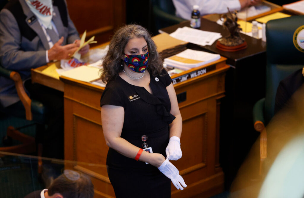 Colorado State Rep. Dafna Michaelson Jenet pulls on latex gloves while wearing a face mask to carry out business on the floor of the House of Representatives Tuesday, May 26, 2020, in downtown Denver. Lawmakers reconvened the 2020 session, which was suspended to deal with the new coronavirus in March, facing the prospect of making deep cuts in the budget Tuesday. (AP Photo/David Zalubowski)
