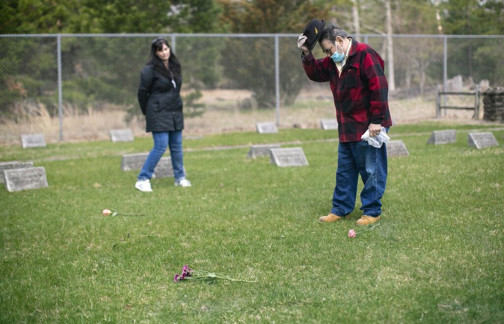 After spreading Bobby's ashes, Chuck bows his dead and takes his hat off during a moment of silence as his friend Joanna Kruse watches. Charles 'Chuck' Carroll is spreading his brother Bobby's ashes at the cemetery on the grounds of the New Lisbon Developmental Center, an institution for people with developmental disabilities. Chuck and Bobby were wrongly placed there as kids in the 1950s and were sexually assaulted for years. Saturday, April 10, 2021. Pemberton, N.J. Aristide Economopoulos | NJ Advance Media