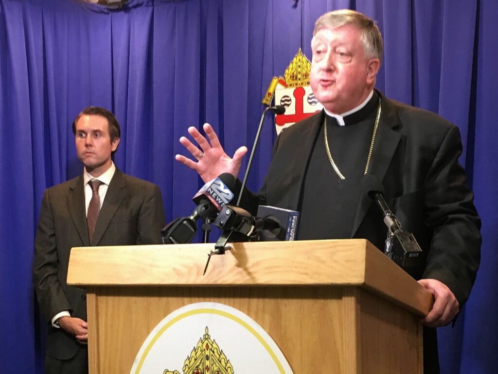 Archbishop Mitchell T. Rozanski, then bishop of the Roman Catholic Diocese of Springfield, talks with reporters at a news conference on Tuesday, June 18, 2019 as Jeffrey J. Trant, director of the diocese's Office of Safe Environment and Victim Assistance, looks on. Rozanski and Trant are defendants in a suit filed by a Chicopee man who says he was sexually assaulted decades ago by the late Bishop Christopher J. Weldon.