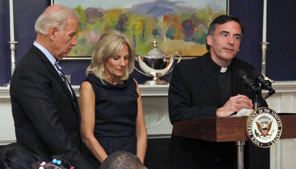 FILE - In this Nov. 22, 2010, file photo, Vice President Joe Biden, left, and his wife, Jill Biden, center, stand with heads bowed as the Rev. Kevin O'Brien says the blessing during a Thanksgiving meal for Wounded Warriors in Washington. Rev. O'Brien, a Jesuit priest who presided over an inaugural Mass for President Joe Biden, has resigned his position as president of Santa Clara University in Northern California, college officials said, after an investigation found he engaged in inappropriate, alcohol-fueled conversations with graduate students. Rev. O'Brien, at the direction of Jesuit officials, has begun a four- to six-month therapeutic outpatient program to address personal issues, including alcohol and stress counseling. (AP Photo/Carolyn Kaster, File)