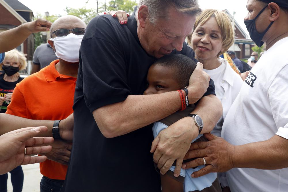 Father Michael Pfleger embraces Jordan-Amman Isiah West-Williams, 9, who was baptized by Father Pfleger, following his reinstatement by Archdiocese of Chicago, Monday, May 24, 2021, in front of St. Sabina Catholic Church in the Auburn Gresham neighborhood in Chicago. (AP Photo/Shafkat Anowar)