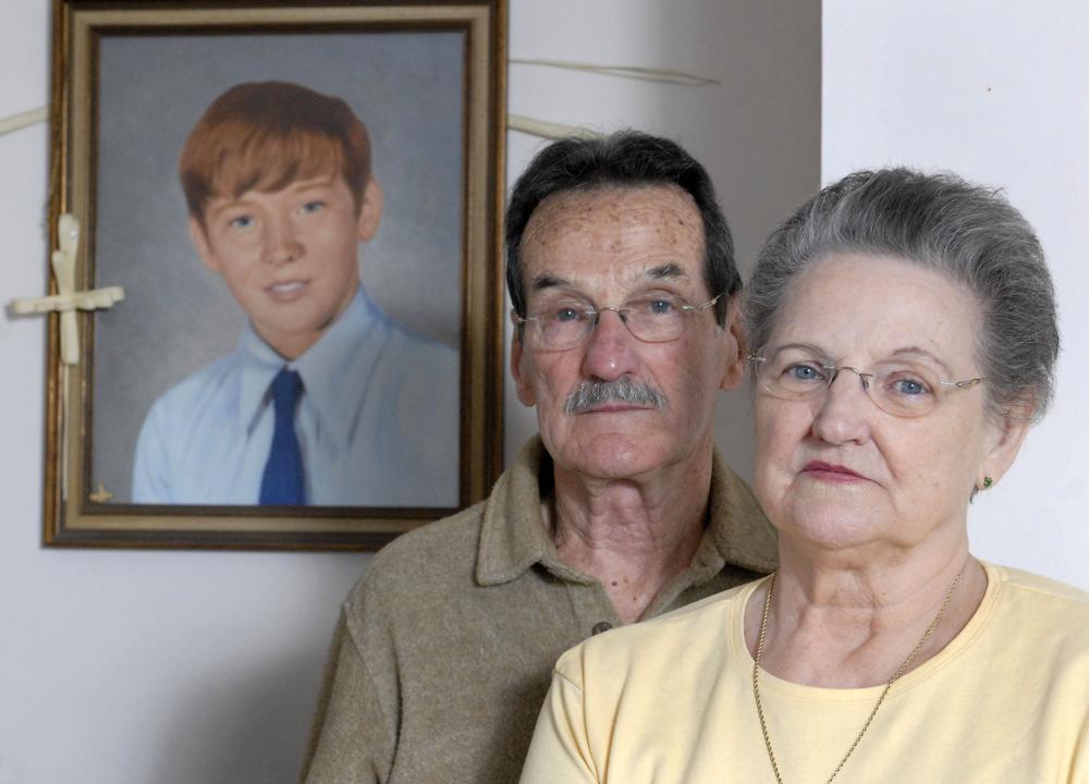 FILE — Carl and Bunny Croteau stand in front of a portrait of their murdered son, Danny, in their Springfield, Mass. home in this Feb. 26, 2008 file photo. The body of Danny Croteau, 13, was found in 1972, in Chicopee, Mass. Rev. Richard R. Lavigne, a former Roman Catholic priest, was the only named suspect but was never charged. Investigators were preparing to seek an arrest warrant for Lavigne, a defrocked Roman Catholic priest long considered a suspect in the 1972 killing of a western Massachusetts altar boy shortly before his death last week, a prosecutor said Monday, May 24, 2021. (AP Photo/Jessica Hill, File)