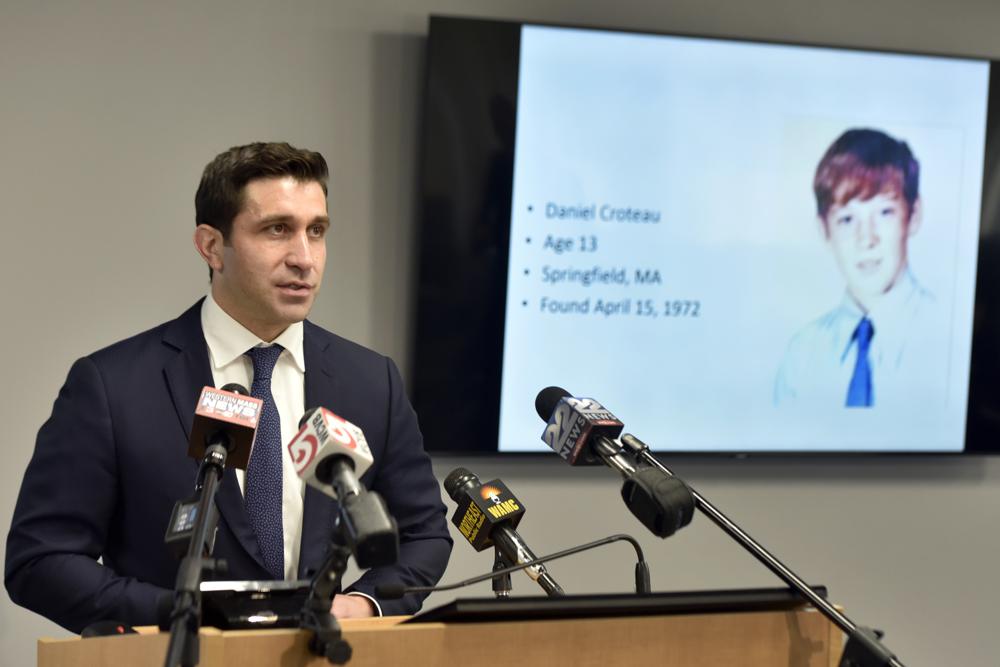 Hampden District Attorney Anthony D. Gulluni, left, speaks during a news conference, Monday, May 24, 2021, in Springfield, Mass., held to announce that defrocked Catholic priest Richard R. Lavigne was about to be arrested for the 1972 killing of alter boy Daniel Croteau, pictured on a screen, right. Investigators were preparing to seek an arrest warrant for the defrocked Roman Catholic priest long considered a suspect in the 1972 killing of the western Massachusetts altar boy shortly before his death last week, a prosecutor said Monday. (Don Treeger/The Republican via AP) o