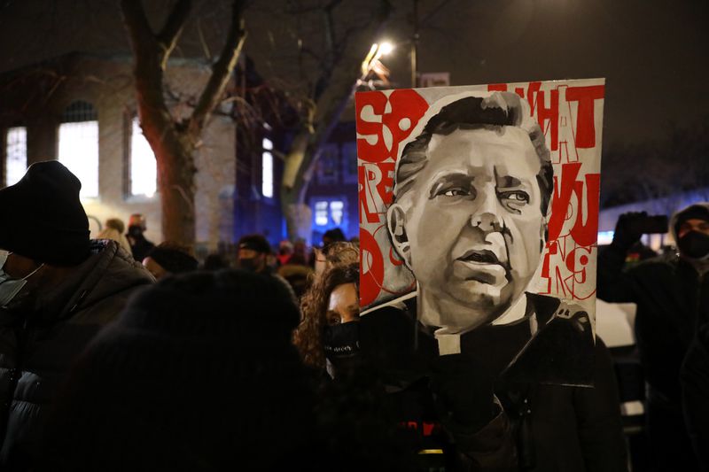 By CHRIS SWEDA / CHICAGO TRIBUNE Sandra Jackson displays an image of the Rev. Michael Pfleger as supporters rally Jan. 8, 2021, in his defense outside St. Sabina Church in Chicago's Auburn Gresham community. (Chris Sweda / Chicago Tribune)