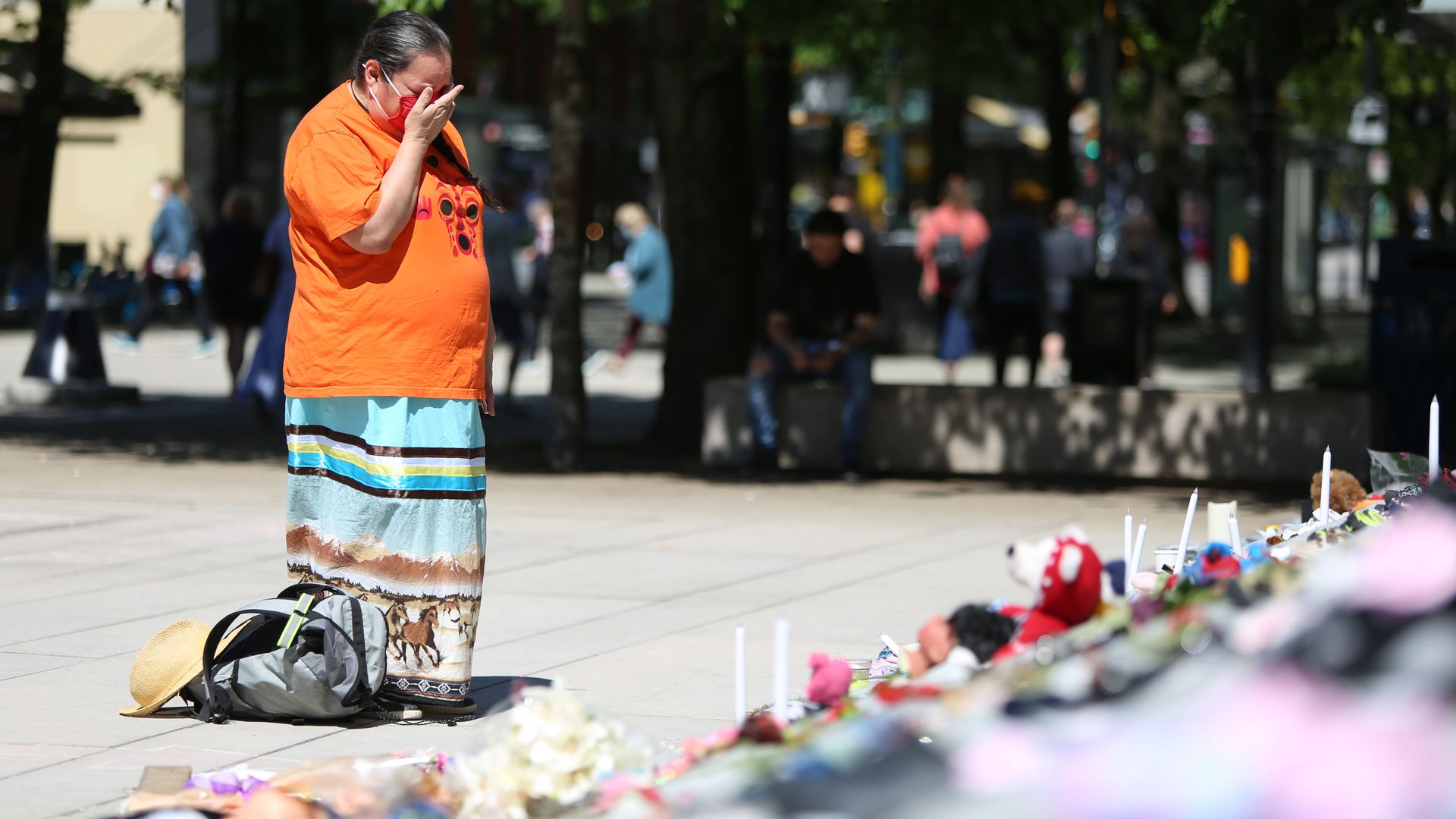 A woman mourns beside 215 pairs of children's shoes outside Vancouver Art Gallery during a memorial in Vancouver, British Columbia, Canada, Saturday, after a mass grave of Indigenous children was found. Photo: Mert Alper Dervis/Anadolu Agency via Getty Images