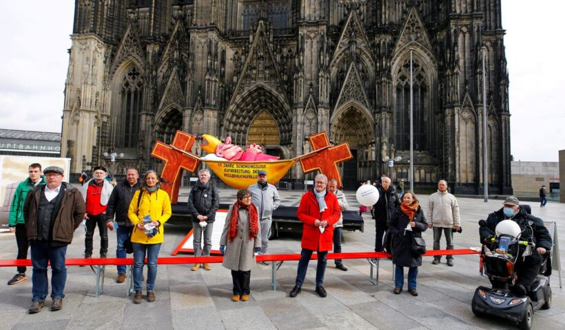 Demonstrators pose for a picture next to a carnival float showing an unnamed bishop from the 2019 "Rosenmontag" (Rose Monday) parade of Duesseldorf placed in front of the Cologne Cathedral by activists of the Giordano Bruno Foundation to protest against sexual abuse by Catholic priests in Cologne, Germany, March 18, 2021. Float reads "11 years of brutal honest reconnaissance of sexual abuse". REUTERS/Thilo Schmuelgen