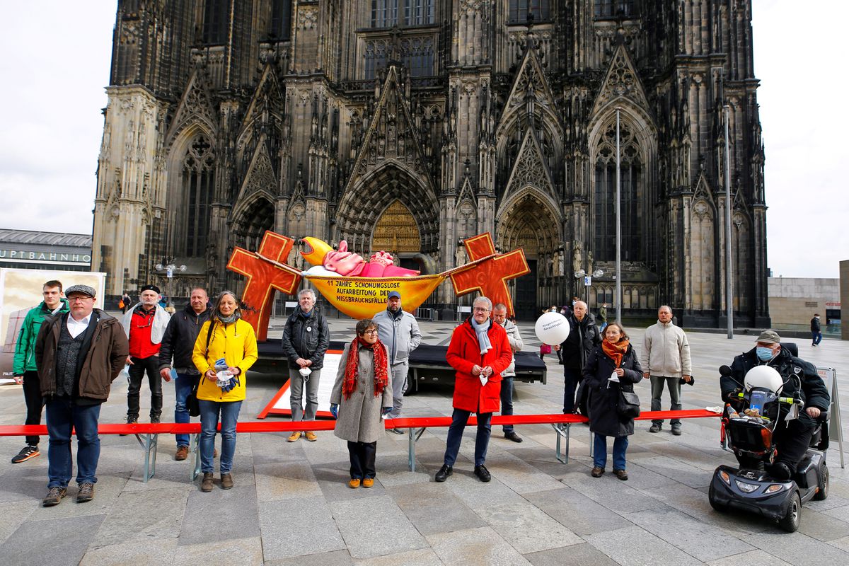 Demonstrators pose for a picture next to a carnival float showing an unnamed bishop from the 2019 "Rosenmontag" (Rose Monday) parade of Duesseldorf placed in front of the Cologne Cathedral by activists of the Giordano Bruno Foundation to protest against sexual abuse by Catholic priests in Cologne, Germany, March 18, 2021. Float reads "11 years of brutal honest reconnaissance of sexual abuse". REUTERS/Thilo Schmuelgen