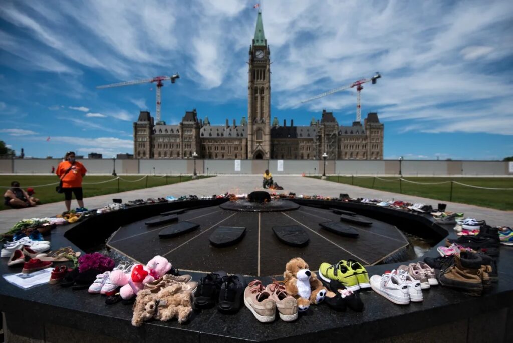 Shoes line the edge of the Centennial Flame on Parliament Hill in memory of the children whose remains are believed to have been found adjacent to the former Kamloops Indian Residential School at Tk’emlups te Secwépemc First Nation in Kamloops, B.C. (Justin Tang/The Canadian Press)