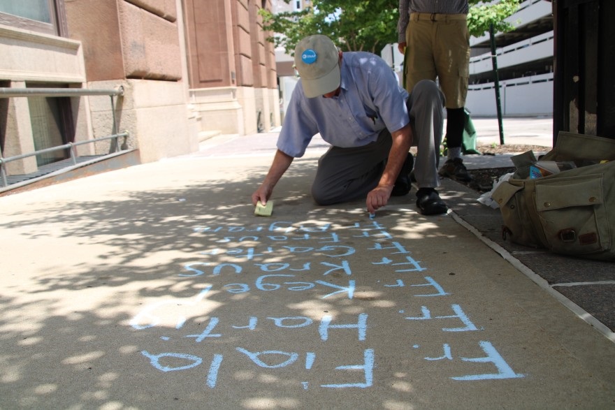 David Clohessy, former executive director of SNAP, the Survivors Network of those Abused by Priests, writes the names of priests left out of the Kansas City diocese's list in front of their headquarters.