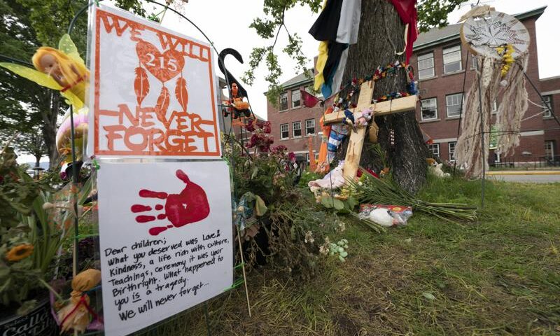 Signs are pictured at a memorial outside the Residential School in Kamloops, British Columbia., Sunday, June, 13, 2021. The remains of 215 children were discovered buried near the former Kamloops Indian Residential School earlier this month. (Jonathan Hayward/The Canadian Press via AP)