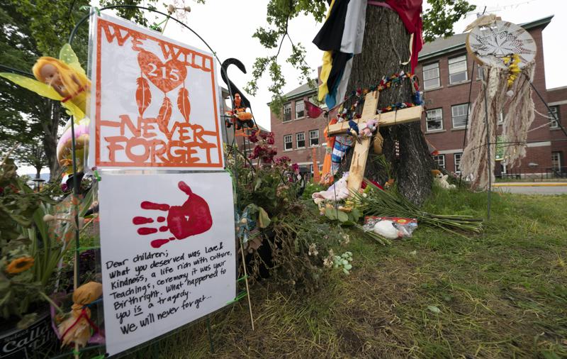 Signs are pictured at a memorial outside the Residential School in Kamloops, British Columbia., Sunday, June, 13, 2021. The remains of 215 children were discovered buried near the former Kamloops Indian Residential School earlier this month. (Jonathan Hayward/The Canadian Press via AP)