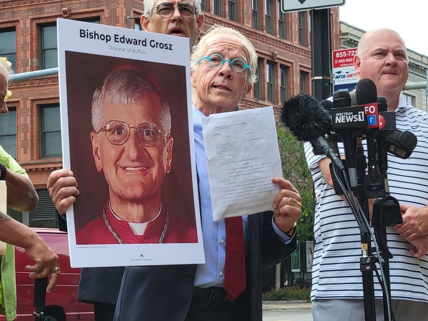 Attorney Jeff Anderson holds up a photo of retired Buffalo Auxiliary Bishop Edward Grosz and a copy of a Child Victims Lawsuit July 14, 2021, outside the Catholic Diocese of Buffalo headquarters.