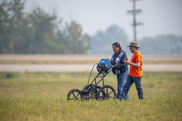 SNC Lavalin engineer Evan Ulmer, right, and Alvin Baptiste use equipment to conduct a search of the grounds at the site of a former Residential School in Delmas, Sask., on July 17, 2021. LIAM RICHARDS/THE CANADIAN PRESS