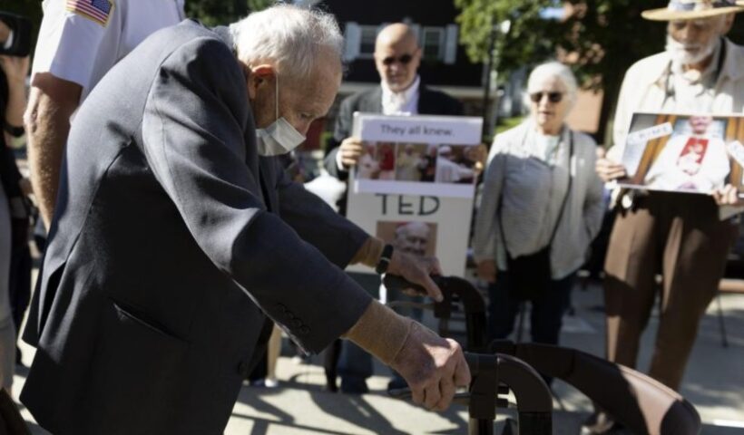 Demonstrators [Skip Shea, Susan Renehan, and Stephen Sheehan] watch as former Cardinal Theodore McCarrick leaves Dedham District Court after his arraignment, Friday, Sept. 3, 2021, in Dedham, Mass. McCarrick has pleaded not guilty to sexually assaulting a 16-year-old boy during a wedding reception in Massachusetts nearly 50 years ago. (AP Photo / Michael Dwyer)