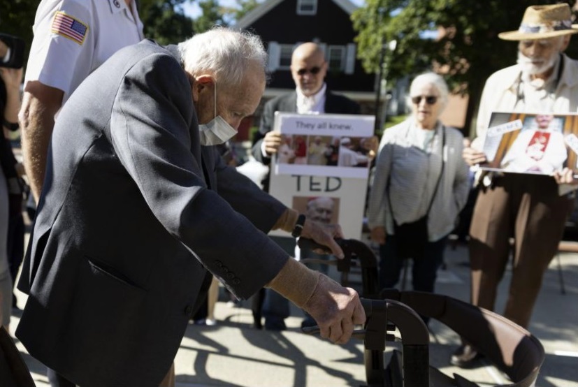 Demonstrators [Skip Shea, Susan Renehan, and Stephen Sheehan] watch as former Cardinal Theodore McCarrick leaves Dedham District Court after his arraignment, Friday, Sept. 3, 2021, in Dedham, Mass. McCarrick has pleaded not guilty to sexually assaulting a 16-year-old boy during a wedding reception in Massachusetts nearly 50 years ago. (AP Photo / Michael Dwyer)