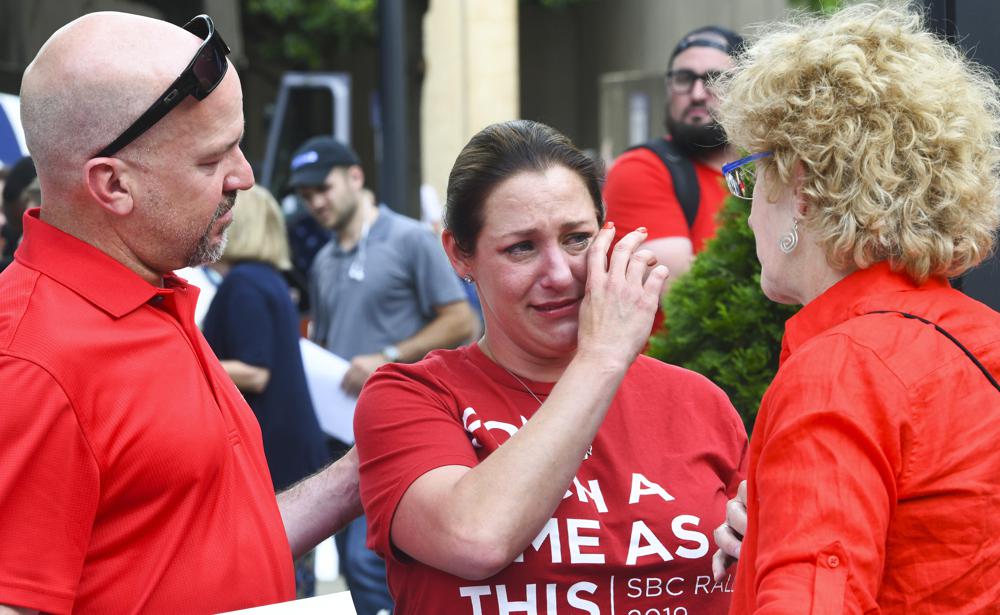 FILE - In this Tuesday, June 11, 2019 file photo, Jules Woodson, center, of Colorado Springs, Colo., is comforted by her boyfriend Ben Smith, left, and Christa Brown while demonstrating outside the Southern Baptist Convention's annual meeting in Birmingham, Ala. First-time attendee Woodson spoke through tears as she described being abused sexually by a Southern Baptist minister. (AP Photo/Julie Bennett, File)