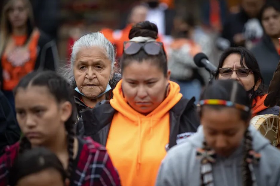 Kamloops Indian Residential School survivor Camille Kenoras, back left, listens as drummers play during a TkÕemlœps te SecwŽpemc ceremony to honour residential school survivors and mark the first National Day for Truth and Reconciliation, in Kamloops, B.C., on Sept. 30, 2021. The Canadian Press / Darryl Dyck