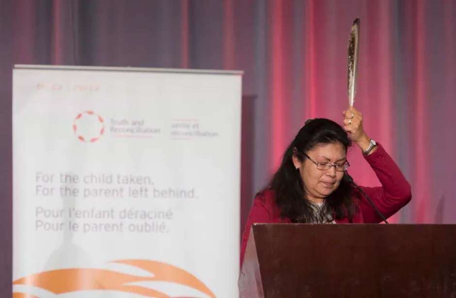 Residential school survivor Madeleine Basile holds up an eagle feather as she speaks during the release of the final report of the Truth and Reconciliation commission, December 2015, in Ottawa. The Canadian Press / Adrian Wyld