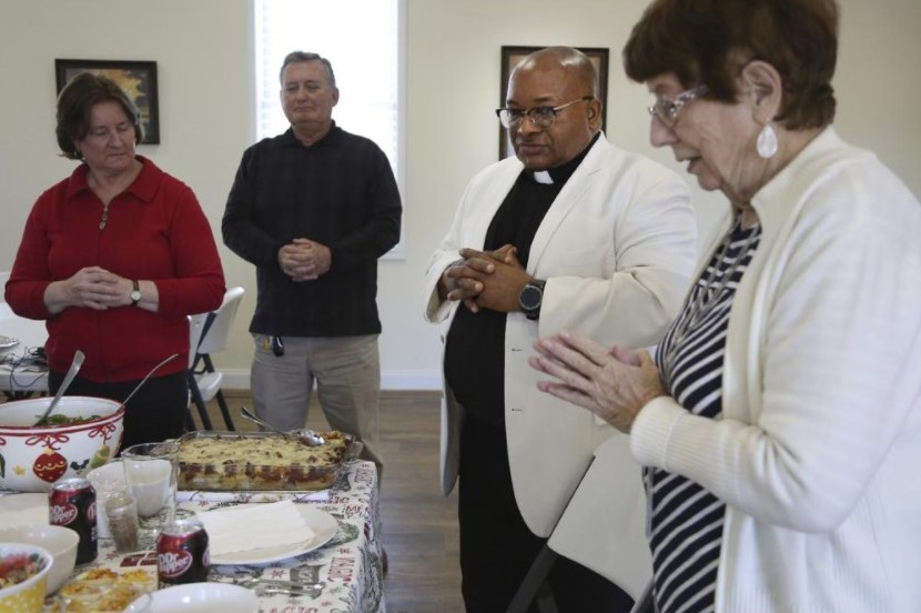 Michele and Frank Varisco, left, pray with the Rev. Athanasius Abanulo and Evelyn Smith, right, before eating lunch at Immaculate Conception Catholic Church in Wedowee, Ala., on Sunday, Dec. 12, 2021. (AP Photo / Jessie Wardarski)