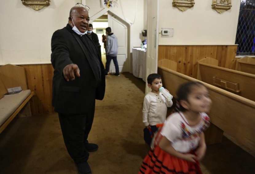 The Rev. Athanasius Abanulo, left, talks to siblings Germany and Samantha Gonzalez at Holy Family Catholic Church in Lanett, Ala., on Saturday, Dec. 11, 2021. Abanulo moved to the U.S. 18 years ago and has since served in several churches from Oakland, Calif., to Nashville, Tenn. He has been with Holy Family for about one year. (AP Photo / Jessie Wardarski)