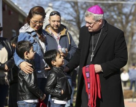 Bishop David Malloy speaks to Aurora resident Maria Velazquez and her sons Joshua, left, 7, and Emiliano, 5, during the Living Stations of the Cross in Aurora on March 25, 2016. (Mike Mantucca / for the Beacon-News)