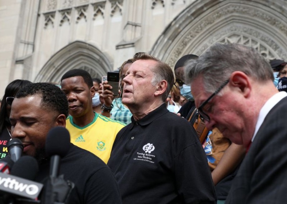 Surrounded by supporters, the Rev. Michael Pfleger, center, closes his eyes in prayer before speaking at a news conference outside St. Sabina Parish in Chicago on May 24, 2021, after an independent review board determined there was insufficient reason to suspect he was guilty of allegations of abuse that had been leveled against him. (Terrence Antonio James / Chicago Tribune)