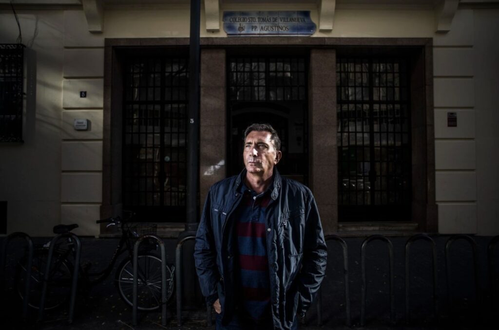 Emilio Boyer, who denounces abuses at the Augustinian school in Valencia, one of the cases included in the EL PAÍS report, in front of the center's façade.  Photo by Samuel Sanchez