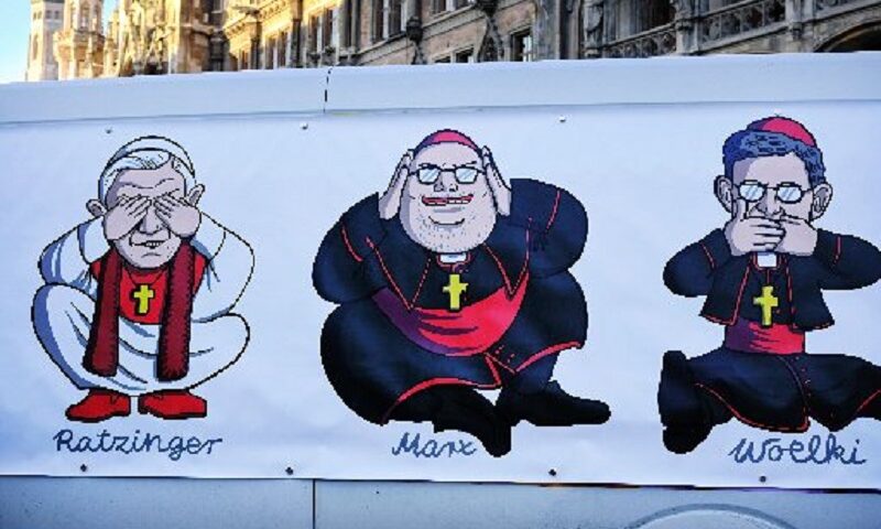 A large poster is attached to a van in Munich Jan. 19, 2022, depicting retired Pope Benedict XVI, Cardinal Reinhard Marx of Munich and Freising, and Archbishop Rainer Maria Woelki of Cologne, during a demonstration in protest of the church’s handling of sexual abuse. (Credit: CNS photo / Dieter Mayr, KNA)