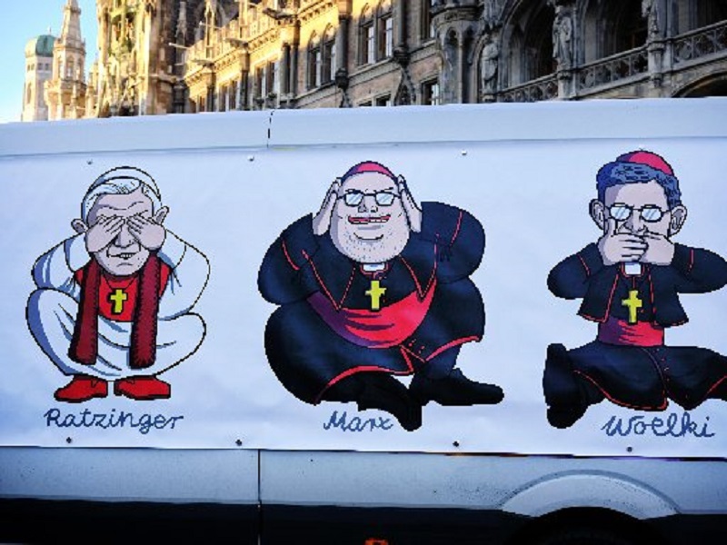 A large poster is attached to a van in Munich Jan. 19, 2022, depicting retired Pope Benedict XVI, Cardinal Reinhard Marx of Munich and Freising, and Archbishop Rainer Maria Woelki of Cologne, during a demonstration in protest of the church’s handling of sexual abuse. (Credit: CNS photo / Dieter Mayr, KNA)