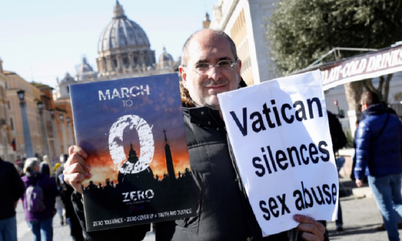 A man poses in front of St Peter Cathedral carrying a banner 'Vatican silences sex abuses' Rome February 23rd 2019. insidefoto srl / Alamy