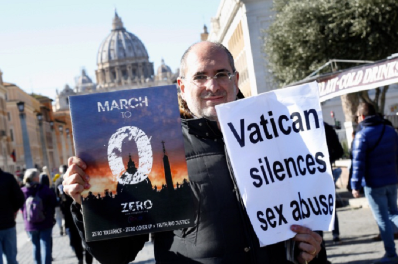 A man poses in front of St Peter Cathedral carrying a banner 'Vatican silences sex abuses' Rome February 23rd 2019. insidefoto srl / Alamy