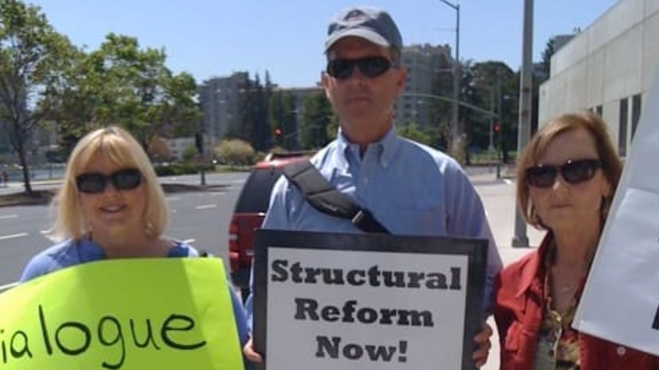 Tim Stier with fellow activists. Full text of the signs: Left: Dialogue, Transparency, and Inclusion Now! Right: Structural Reform Now! Include the Excluded: Women, Gay Persons, Abuse Survivors. Source: https://timstier.weebly.com/about.html