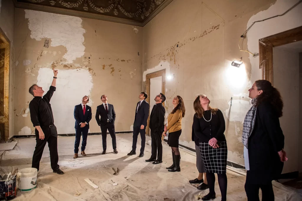 The Rev. Andrew Small, left, with staff of the Pontifical Commission for the Protection of Minors, visiting a ruined chapel at the Palazzo Maffei Marescotti in Rome, which also houses the commission’s new offices.Credit...Stephanie Gengotti for The New York Times