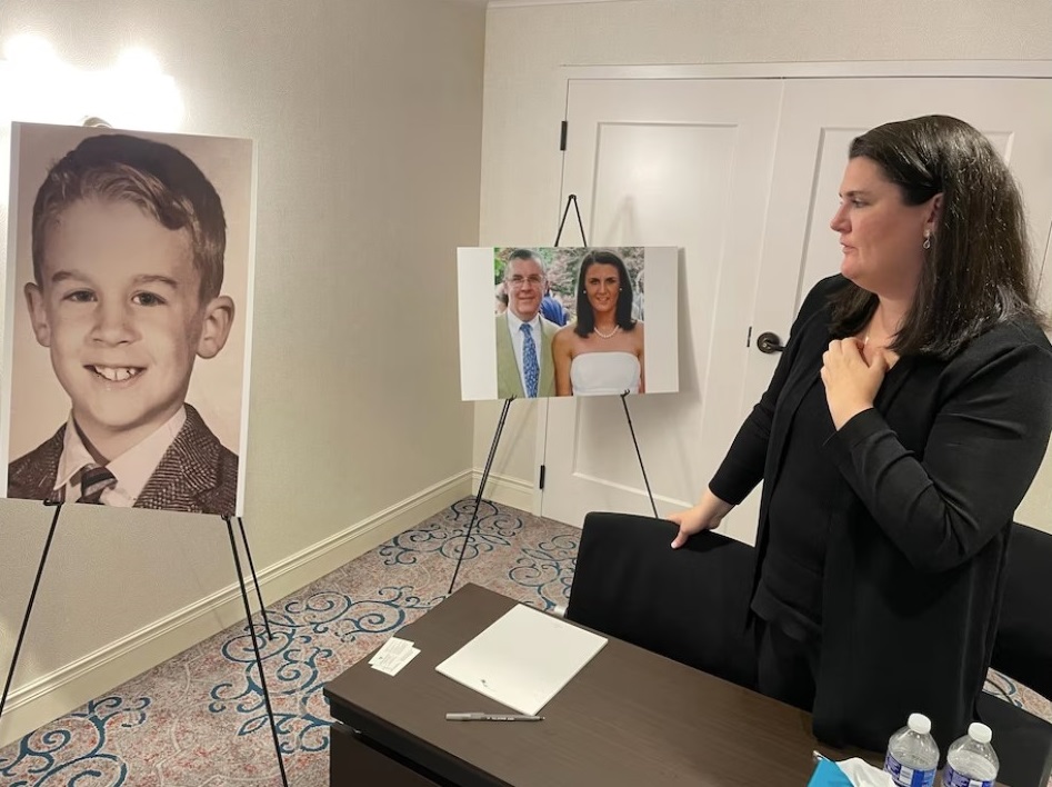 Flannery Gallagher looks at a childhood photo of her father, the late Francis X. Gallagher, Jr., at a press conference announcing a lawsuit against the Archdiocese of Baltimore and St. Mary's Seminary, on June 27, 2023, in Baltimore, Md. (Michelle Boorstein/The Washington Post)